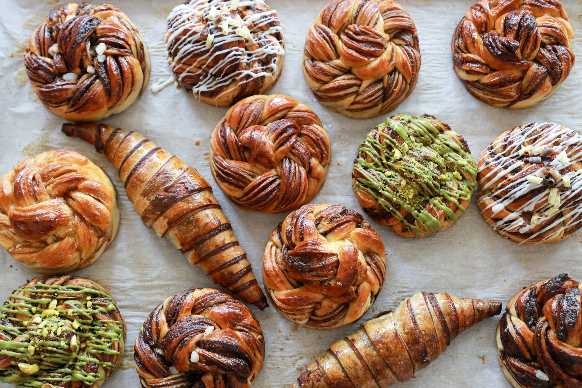 Assorted handcrafted pastry twists and croissants arranged on a baking tray